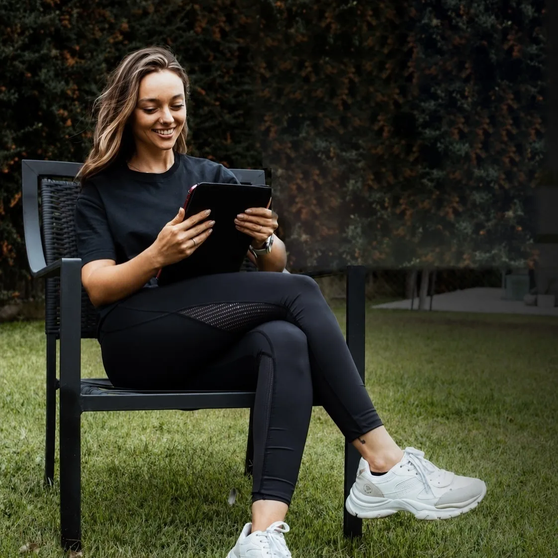 Sofi revisa un plan de entrenamiento en la tablet, sentada en el jardín